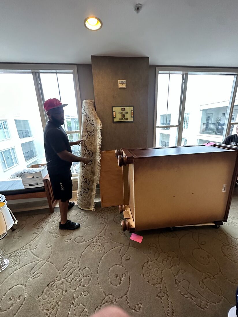 A Heavy Lifters mover carefully carrying a heavy dresser — movers serving St. Augustine, FL